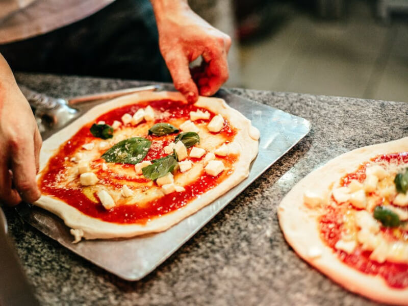 A man making pizza in an Italian cooking class.